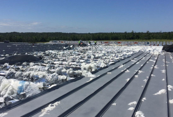 Storm damaged roof with work crew visible in background