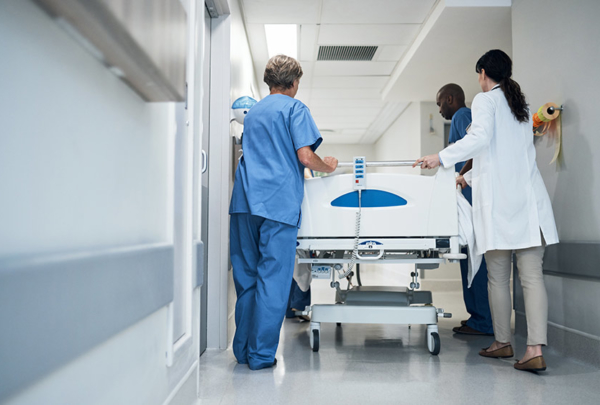 Rearview shot of a medical team pushing a patient down the hallway in a gurney.