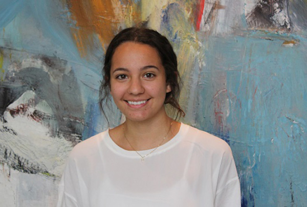 Haskell intern Camila Moreno smiling in front of colorful artwork.