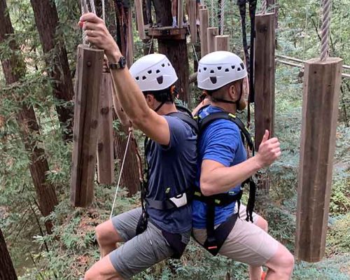 Livermore employees using teamwork to traverse a cable bridge on Mount Hermon