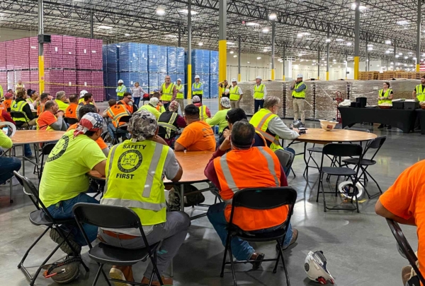 A Haskell construction crew gathers for a meeting in Bang Energy's giant warehouse