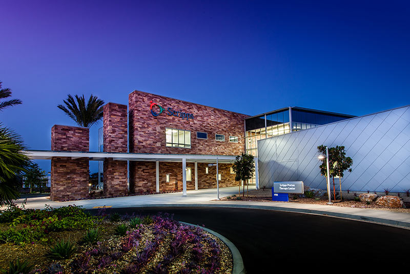 Exterior photo of California Proton Cancer Therapy Center at dusk of entrance drive and landscaping.